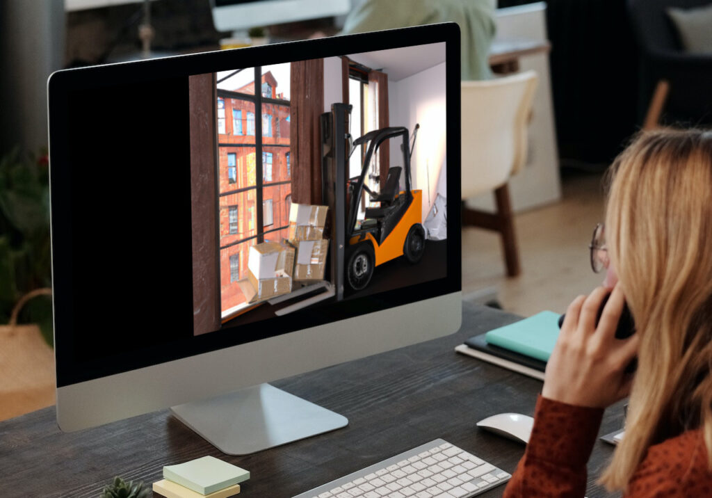 Woman on the phone sees the image of a forklift in a highrise apartment near a window on her imac